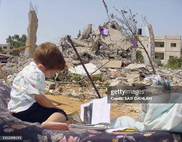 Palestinian child sits on a rescued mattress looking at pictures in a book close to the flattened home of Mazen Fukha who was arrested three days ago...