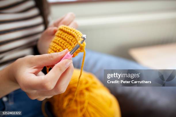 young woman crocheting with yellow wool - crocheting stock pictures, royalty-free photos & images