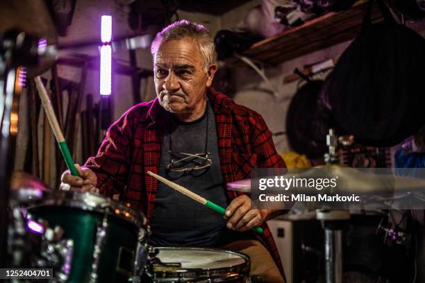 un hombre mayor practica jugando a bunje - recordando los días más jóvenes - hombre mayor feliz - playing drums fotografías e imágenes de stock