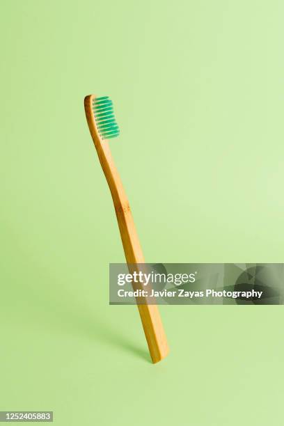 floating bamboo toothbrush on a green background - escova de dentes imagens e fotografias de stock