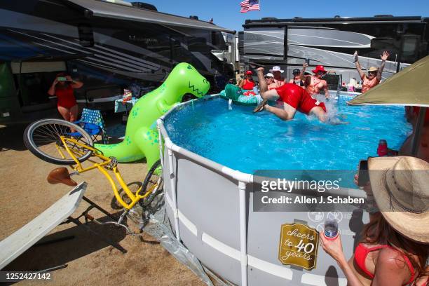 While his wife Nicole, right, records on her phone, Gary Colle, of San Diego jumps his bike off a table ramp into the pool to escape the triple-digit...