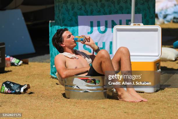 Amid triple-digit temperatures, Owen Strassner, of Los Angeles, drinks a cold drink while relaxing in a small tub of water at the campground The...