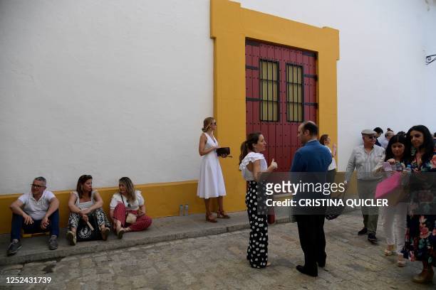 Visitors hide from the sun as they arrive for the Feria de Abril bullfighting festival at La Maestranza bullring in Seville on April 30, 2023.