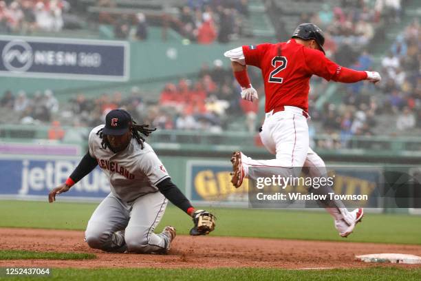 Josh Bell of the Cleveland Guardians misses the tag after fielding a wide throw as Justin Turner of the Boston Red Sox is safe at first during the...