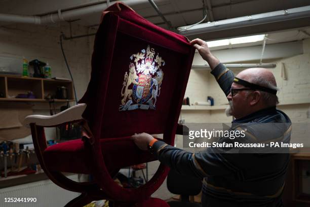 Upholsterer Alex Burnett works on one of the throne chairs which will be used for the coronation of King Charles III and the Queen Consort, at A.T....