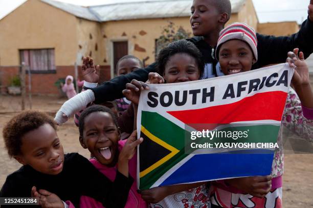 Children of a Bloemfontein township hold a South African flag a few hours before the Fifa Confederations Cup football match Spain vs South Africa on...