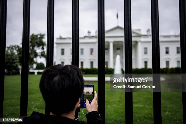 Visitor takes a photograph on his cell phone of the White House through the fence around the North Lawn on April 30, 2023 in Washington, DC.