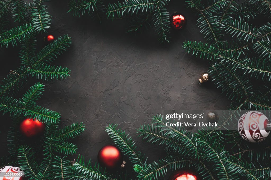 Christmas composition. Frame made of christmas gifts, pine branches, toys on black background. Flat lay, top view, copy space.