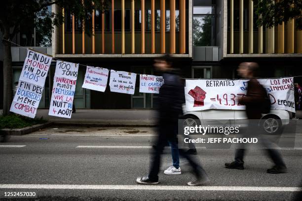 Protesters walk past anti-government placards strung beside a road as they take part in a demonstration on May Day , to mark the international day of...