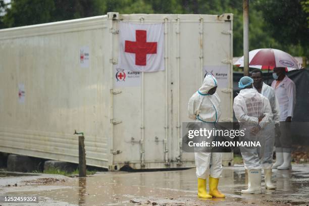 Kenyan government officials and pathologists wearing protective clothing stand by before the start of postmortem analysis on victims of the Shakahola...