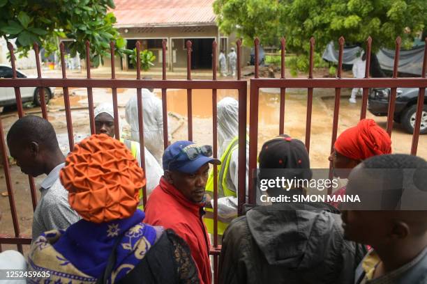 Friends and relatives of victims stand outside the gates as they await the start of postmortem analysis on victims of the Shakahola massacre at the...