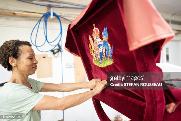 Upholsterer Beatrice Ekwalla works on the Queen Consort's throne chair which will be used for the coronation of Britain's King Charles III and...