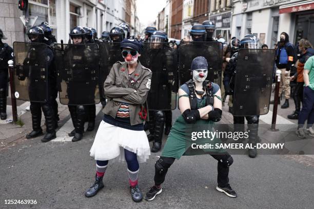 Protesters dressed as clowns pose in front of French police in riot gear as they take part in a demonstration on May Day , to mark the international...