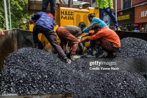Kashmiri labourers work on a road paver to lay asphalt concrete on a road in the city center during the International Labor Day on May 01, 2023 in...