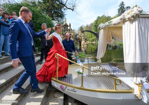 May 2023, Saxony, Gablenz: Michael Kretschmer , Prime Minister of Saxony, leads the Kromlau Flower King Stefanie Engler onto the newly christened...