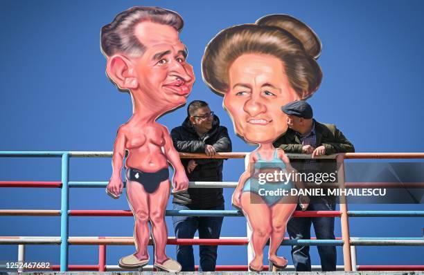 Visitors pose on a walkway decorated with caricatures of late Romanian communist dictator Nicolae Ceausescu and his wife Elena Ceausescu during "The...