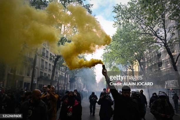 Protester brandishes a yellow smoke grenade as he takes part in a demonstration on May Day , to mark the international day of the workers, more than...