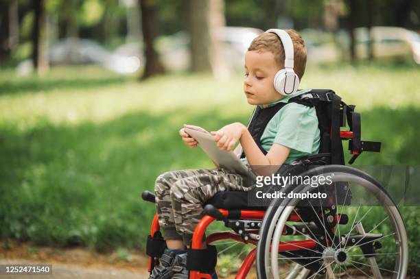 disabled young boy using digital tablet - special needs children stock pictures, royalty-free photos & images