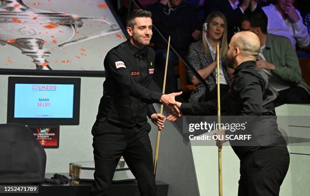 England's Mark Selby and Belgium's Luca Brecel shake hands at the end of the afternoon session on day two of their World Championship Snooker final...