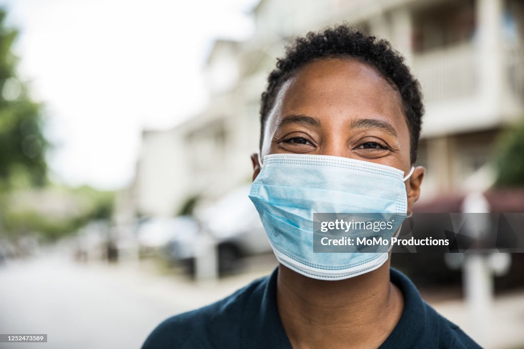 Young woman wearing surgical mask in front of home