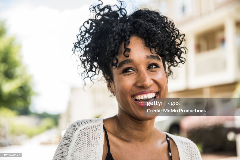 Portrait of young woman smiling in front of home