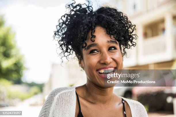 portrait of young woman smiling in front of home - stralende lach stockfoto's en -beelden