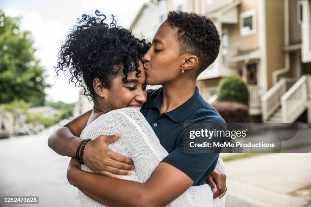 lesbian couple embracing in front of home - gay couple kissing fotografías e imágenes de stock