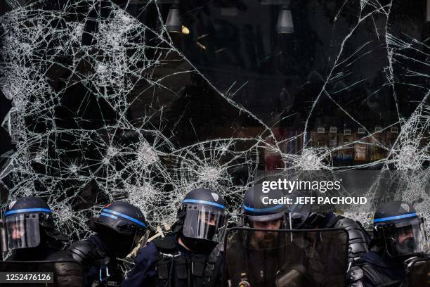 Police officers stand in front of the broken window of a shop during a demonstration on May Day to mark the international day of the workers, more...