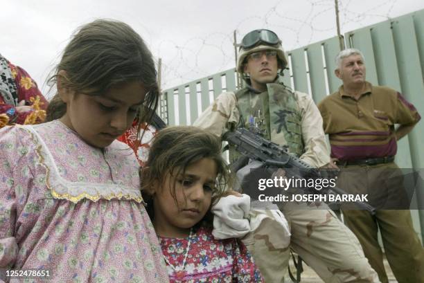 Iraqi children wait at a US chechpoint in the city of Tikrit 15 April 2003. The Pentagon said it was not yet ready to declare victory after nearly...