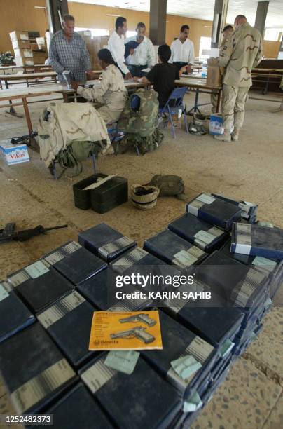 Military police distribute 9mm Beretta handguns to Iraqi policemen 28 May 2003 in Baghdad. The new Iraqi police force were also issued police...