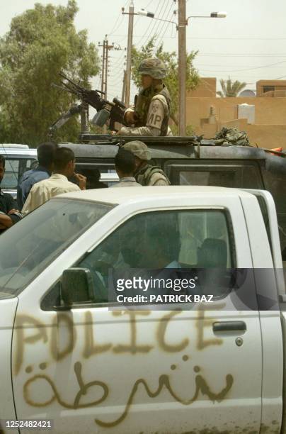 Iraqi police wearing new uniforms drive their pickup truck, emblazoned with the words "Police" in English and Arabic, past US military police 28 May...
