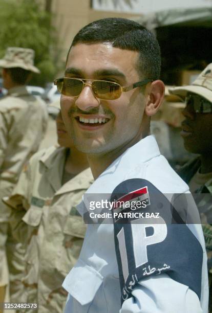 Young Iraqi policeman smiles in his new police garb, in which the Arabic phrase 'God is Great', or 'Allahu Akbar', was removed from the Iraqi flag,...
