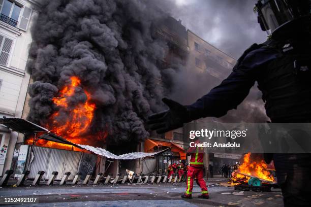 French riot poilce surrounding a building on fire during a protest on International Workers' day against the government's pension reform in Paris,...