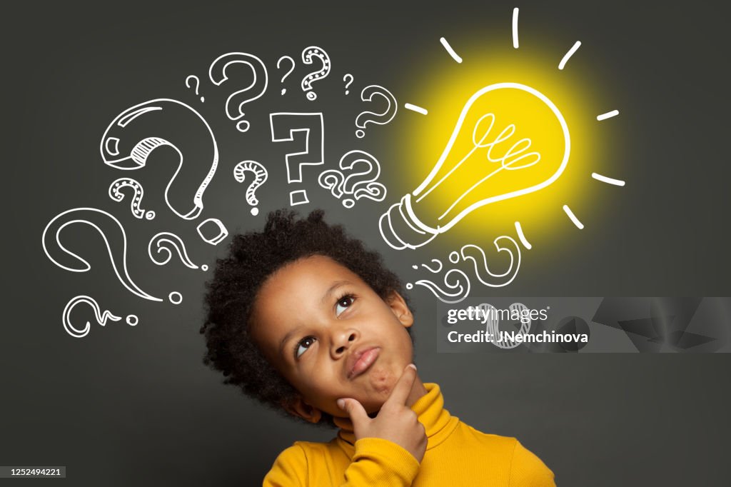 Thinking child boy on black background with light bulb and question marks. Brainstorming and idea concept