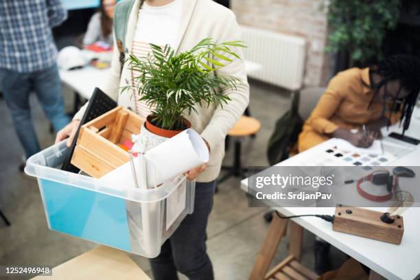 an unrecognizable male employee carrying his belongings while leaving the office after being fired - possession stock pictures, royalty-free photos & images