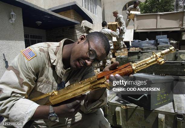 Soldier from the 3rd Infantry Division takes a close look at a golden Kalashnikov ingraved with an Arabic sentence reading "A gift from Iraqi...