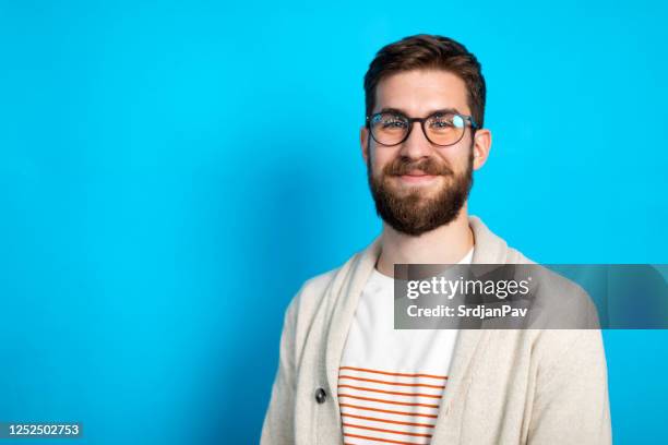 jonge kaukasische mens die tegen blauwe achtergrond stelt - male man portrait one person business confident background stockfoto's en -beelden