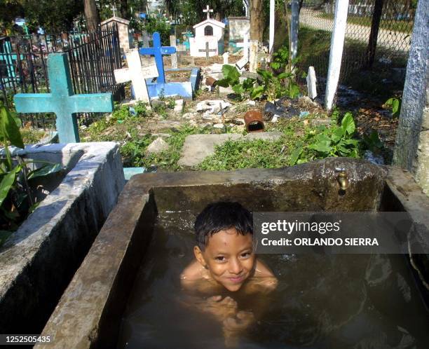 Boy takes a bath at the "La Puerta" cemetery in San Pedro Sula, 240 km north of Tegucigalpa, Honduras 27 April 2002. Lisa Lopes, the pop singer for...