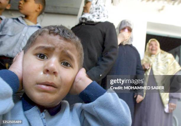 The brother of Palestinian Ahmad al-Ashram weeps as he blocks his ears during the funeral 09 April 2003 of his 12-year-old brother and six other...