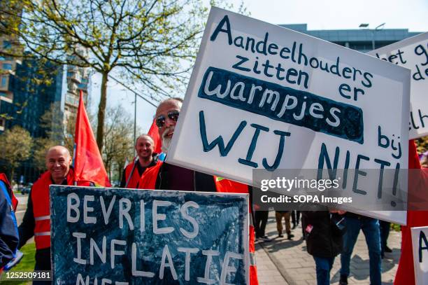 Man is seen behind several placards in support of workers. On the day of International Workers' Day, also known as Labour Day, in Amsterdam people...