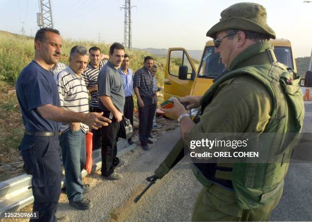 An Israeli soldier checks the IDs of Palestinians at the Tapuah junction checkpoint in the West Bank, south of Nablus 14 May 2003. Israeli Prime...
