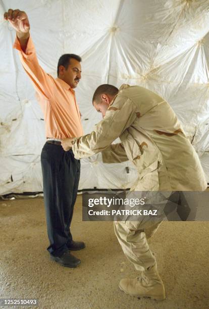 Jonathan Stone from the US Military Police measures the waist of an Iraqi man 28 May 2003 in Baghdad before he is given a new Iraqi police uniform to...