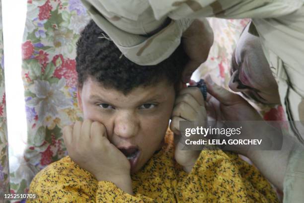 Army combat medic Joe Ferrand with the 92nd Airborne out of Fort Bragg, North Carolina, checks the ears of an Iraqi boy during a medical checkup 11...