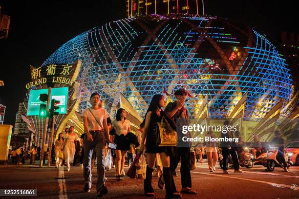 Visitors cross the street in front of the Grand Lisboa casino resort, operated by SJM Holdings Ltd., during Golden Week at night in Macau, China, on...