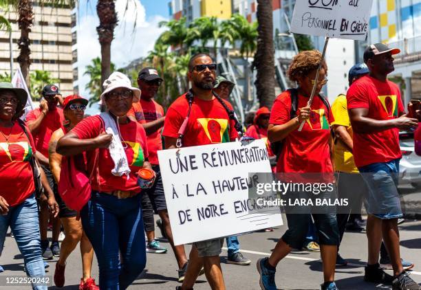 Protesters march, holding a placard reading "A remuneration worthy of our commitment", during a demonstration on May Day to mark the international...