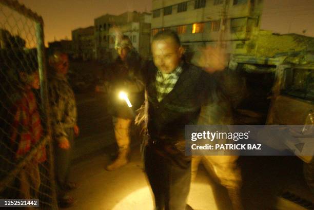 Troops from the First Armoured Division, the Second Battalion and the Third Field Artillery Regiment search an Iraqi civilian as they raid a bar in...