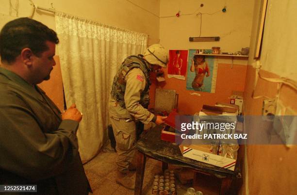 An Iraqi civilian looks at a US soldier as he searches for weapons at a bar in Baghdad in the early hours of 20 November 2003. US troops from the...