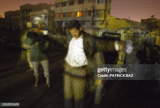 Troops from the First Armoured Division, the Second Battalion and the Third Field Artillery Regiment search an Iraqi civilian as they raid a bar in...