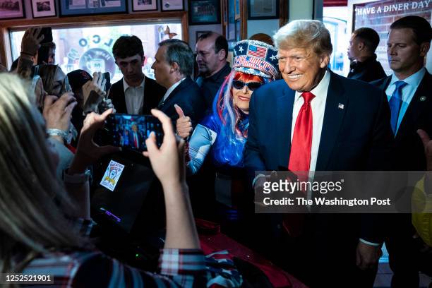 Manchester, NH Former President Donald Trump greets Micki Larson-Olson while visiting the Red Arrow Diner after a campaign rally on Thursday, April...