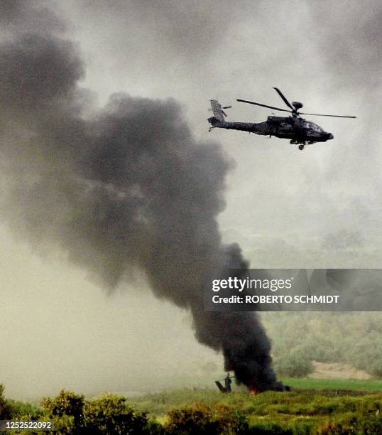 Blackhawk helicopter flies low over another burning on seconds after it crashed landed into a field some 4km away from the main US base in the...